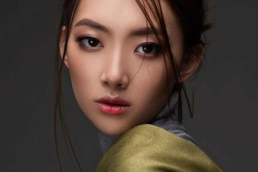 asian woman looking over her shoulder wearing green shirt